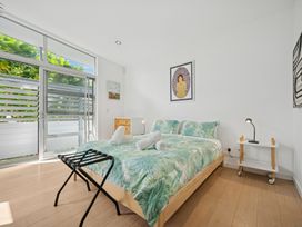 A bedroom with a bed, bedside table, and window at Peka Peka Beach House - Waikanae