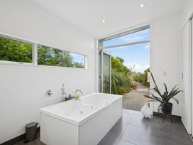A bathroom with a bathtub and windows at Peka Peka Beach House - Waikanae