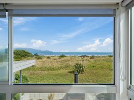 A view from a window showing grass and ocean at Peka Peka Beach House - Waikanae Holiday Home