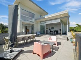 An outdoor patio with a dining table and seating at Peka Peka Beach House - Waikanae