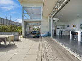 An outdoor patio with a table and chairs at Peka Peka Beach House - Waikanae