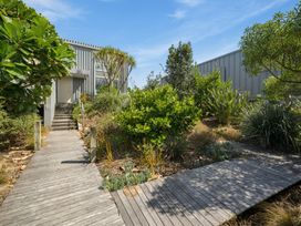 A pathway leading to a building surrounded by greenery at Peka Peka Beach House - Waikanae