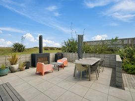 An outdoor patio with seating and a fireplace at Peka Peka Beach House - Waikanae