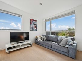 A living room with a television and a sofa at Peka Peka Beach House - Waikanae