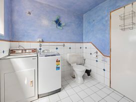 A laundry room with appliances and a toilet at Hawksie Place in Reporaa