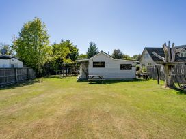 A backyard with a house, table and trees at Wanaka Holiday Home in Wanaka