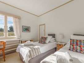 A bedroom with two beds and a chair at Kettle House - Upper Moutere Holiday Home