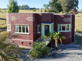 A house with windows and palm trees at Kettle House - Upper Moutere Holiday Home