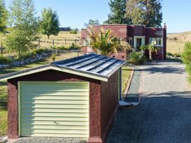 A view of a house and garage with a driveway at Kettle House - Upper Moutere Holiday Home
