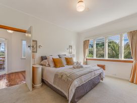 A bedroom with a bed and windows at Kettle House - Upper Moutere Holiday Home