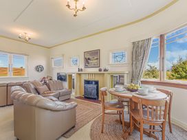 A living room with a sofa and dining area at Kettle House - Upper Moutere Holiday Home