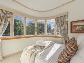 A bedroom with a bed and large windows at Kettle House - Upper Moutere Holiday Home