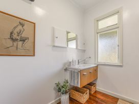 A bathroom with a sink, mirror and artwork at Kettle House - Upper Moutere Holiday Home