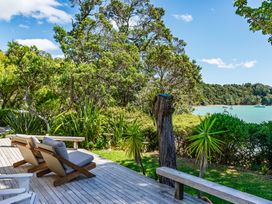 An outdoor space with a deck and chairs overlooking a water view at Parekura Bay in Hikurangi