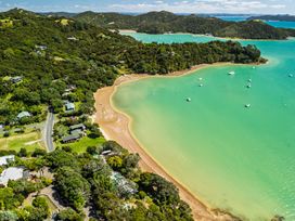 An aerial view of a beach with houses and boats at Parekura Bay Hikurangi