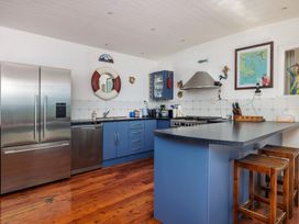 A kitchen with appliances and bar stools at Parekura Bay Hikurangi