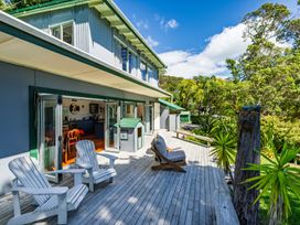 An outdoor terrace with wooden chairs and a table at Parekura Bay in Hikurangi