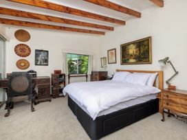 A bedroom with a bed, desk, and decorations at Parekura Bay Hikurangi