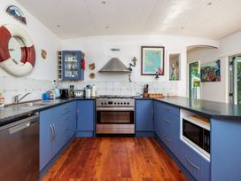 A kitchen with appliances and blue cabinets at Parekura Bay in Hikurangi