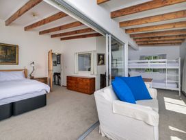 A bedroom with a bed, bunk bed, and sofa at Parekura Bay Hikurangi