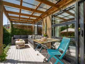 An outdoor patio with a sofa, table, and chairs at River Cottage - Whitianga Holiday Home