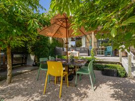An outdoor patio with a table and chairs at River Cottage - Whitianga Holiday Home