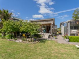An outdoor area with a house, garden, and seating at River Cottage - Whitianga Holiday Home