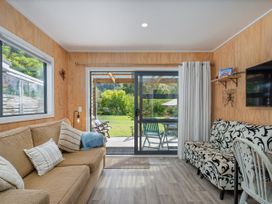 A living room with sofa and television at River Cottage - Whitianga Holiday Home
