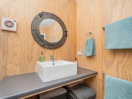 A bathroom with a sink and mirror at River Cottage - Whitianga Holiday Home
