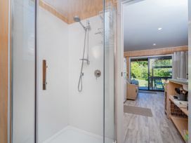 A bathroom with a shower and view to the living area at River Cottage - Whitianga Holiday Home
