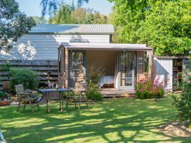 A garden with a cabin, table, and chairs at River Cottage - Whitianga Holiday Home, Whitianga