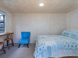 A bedroom with a bed and chair at River Cottage - Whitianga Holiday Home Whitianga