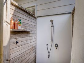 A shower with a shelf holding bottles at River Cottage - Whitianga Holiday Home, Whitianga
