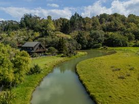 A house next to a river in a green area at River Cottage - Whitianga Holiday Home in Whitianga