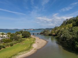A river with a bridge and trees at River Cottage - Whitianga Holiday Home, Whitianga