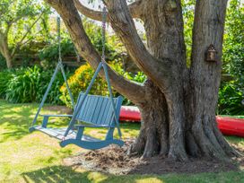 A swing hanging from a tree in the garden at River Cottage - Whitianga Holiday Home Whitianga
