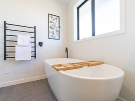 A bathroom with a bathtub and towel rack at Oraka Scenery - Te Anau Holiday Home Te Anau