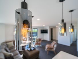 A light fixture in a living room with a couch and TV at Oraka Scenery - Te Anau Holiday Home