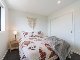 A bedroom with a bed and bedside lamp at Oraka Scenery - Te Anau Holiday Home