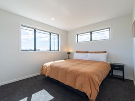 A bedroom with a bed and windows at Oraka Scenery - Te Anau Holiday Home, Te Anau