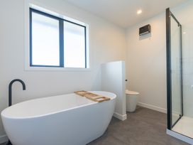 A bathroom with a bathtub, toilet, and shower at Oraka Scenery - Te Anau Holiday Home