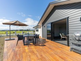 An outdoor dining area with a table, chairs, and umbrella at Oraka Scenery - Te Anau
