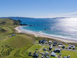 An aerial view of a beach with houses and hills at Opito Bay Holiday Home Opito Bay