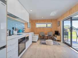 A living room with kitchen appliances and seating at Opito Bay Holiday Home in Opito Bay