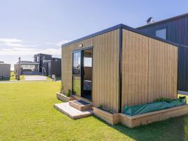 A wooden cabin with a deck and plants in an outdoor area at Opito Bay Holiday Home, Opito Bay