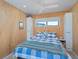 A bedroom with a bed and ceiling fan at Opito Bay Holiday Home Opito Bay