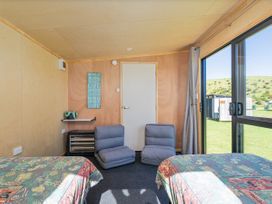 A bedroom with two beds and chairs at Opito Bay Holiday Home in Opito Bay