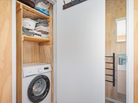 A laundry room with shelves of towels and a washing machine at Opito Bay Holiday Home in Opito Bay