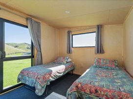 A bedroom with two beds and a window at Opito Bay Holiday Home, Opito Bay
