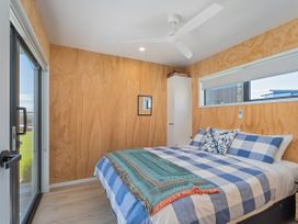 A bedroom with a bed and a fan at Opito Bay Holiday Home in Opito Bay
